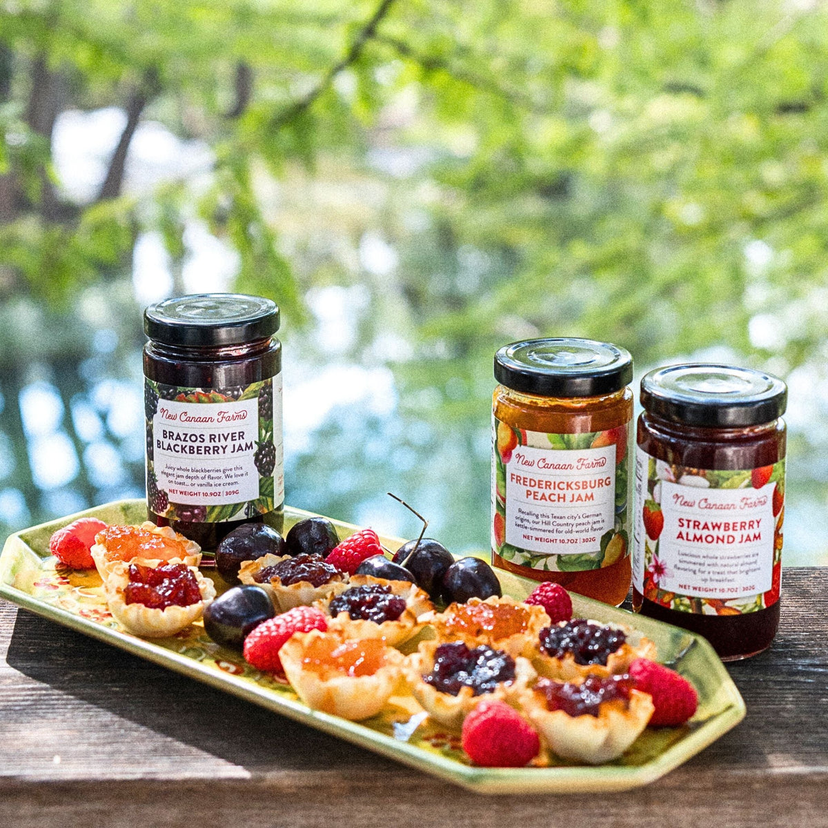 Brazos River Blackberry, Fredericksburg Peach and Strawberry Almond jams beside a tray of jam tarts and berries