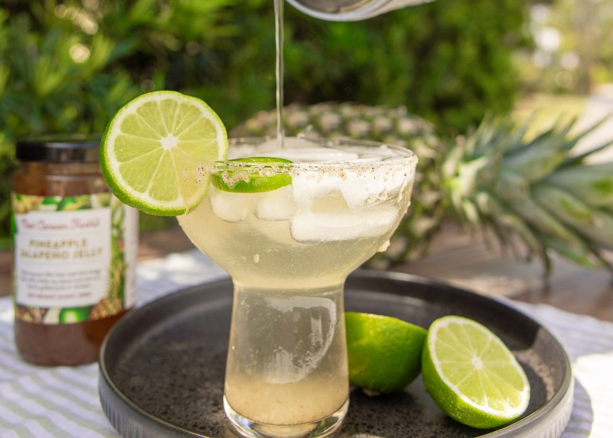 A margarita with lime beside a jar of Pineapple Jalapeño Jelly