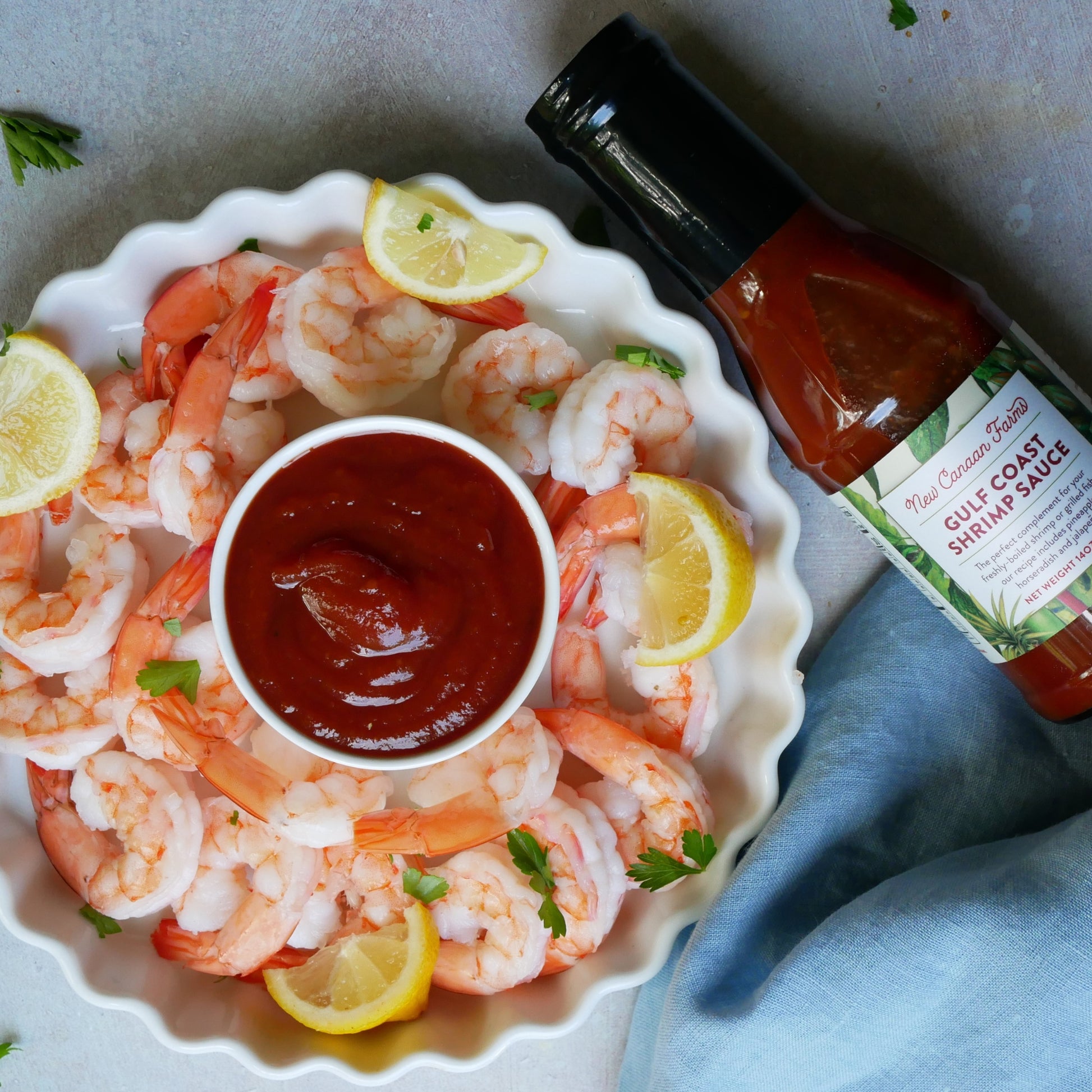 Platter of shrimp with lemon slices and a bottle of New Canaan Farms Gulf Coast shrimp sauce
