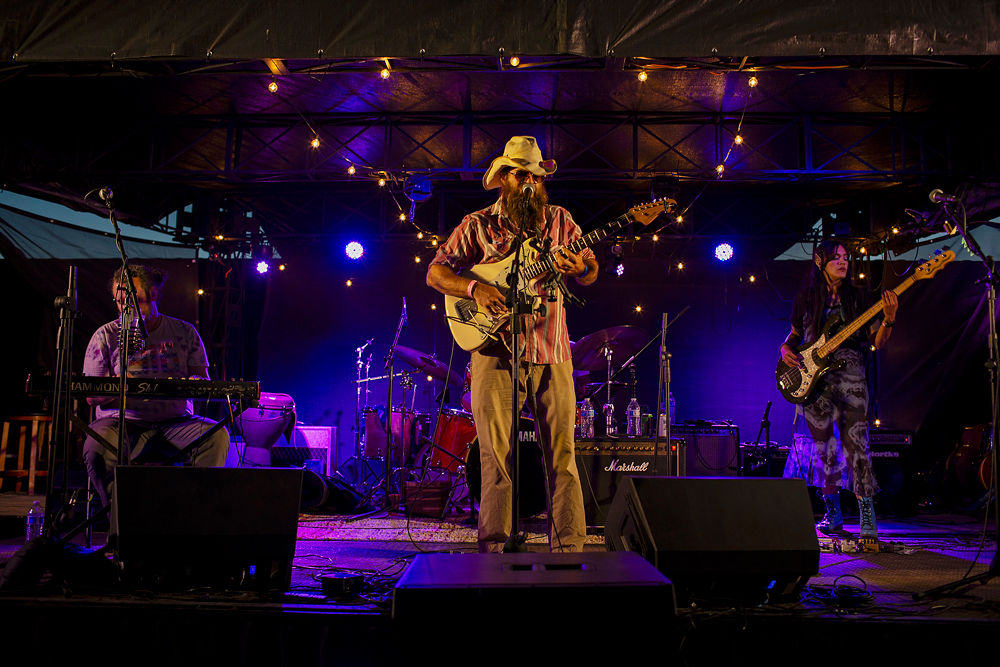 Band performing on stage with musical instruments under a dark sky.