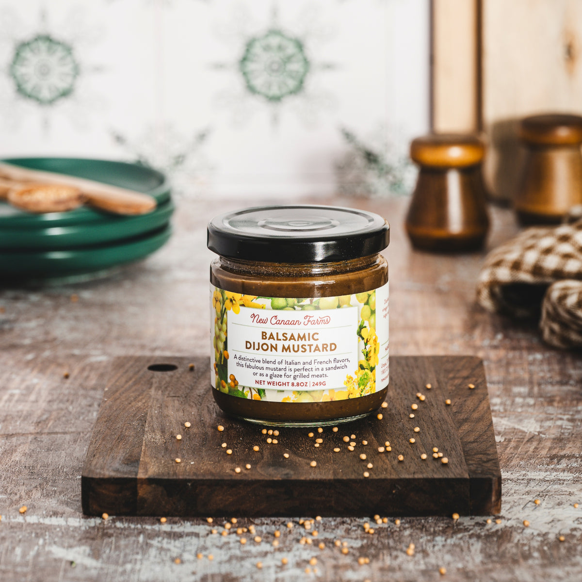 Jar of balsamic Dijon mustard on a wooden cutting board with a blurred kitchen background.