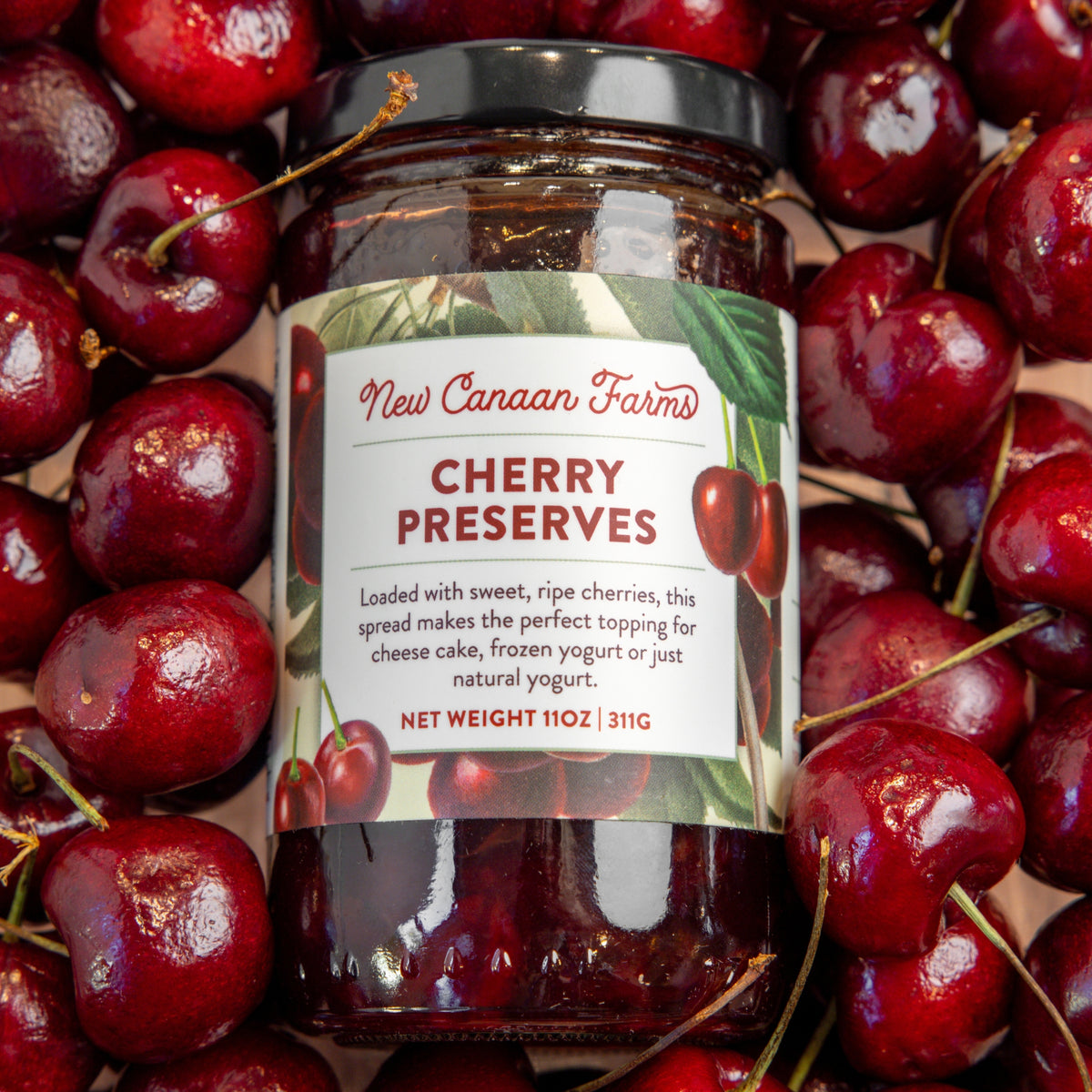 Jar of New Canaan Farms Cherry Preserves surrounded by cherries