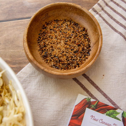 Wooden bowl with seasoning on a striped cloth with a spice packet.