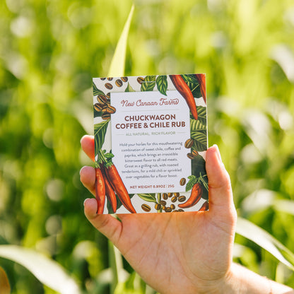 Hand holding a box of Chuckwagon Coffee & Chile Rub against a green outdoor background