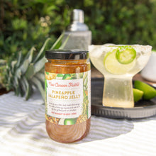 Jar of Pineapple Jalapeno Jelly on a table with a cocktail in the background