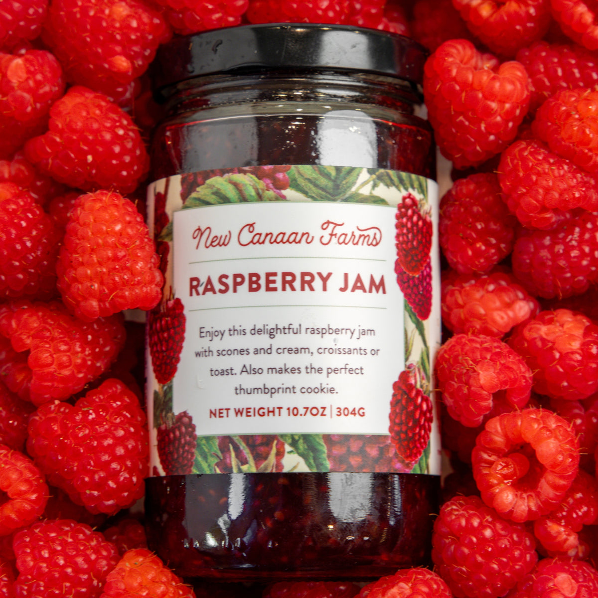 Jar of New Canaan Farms Raspberry Jam surrounded by fresh raspberries