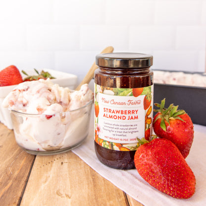 Jar of New Canaan Farms Strawberry Almond Jam with strawberries on a wooden table