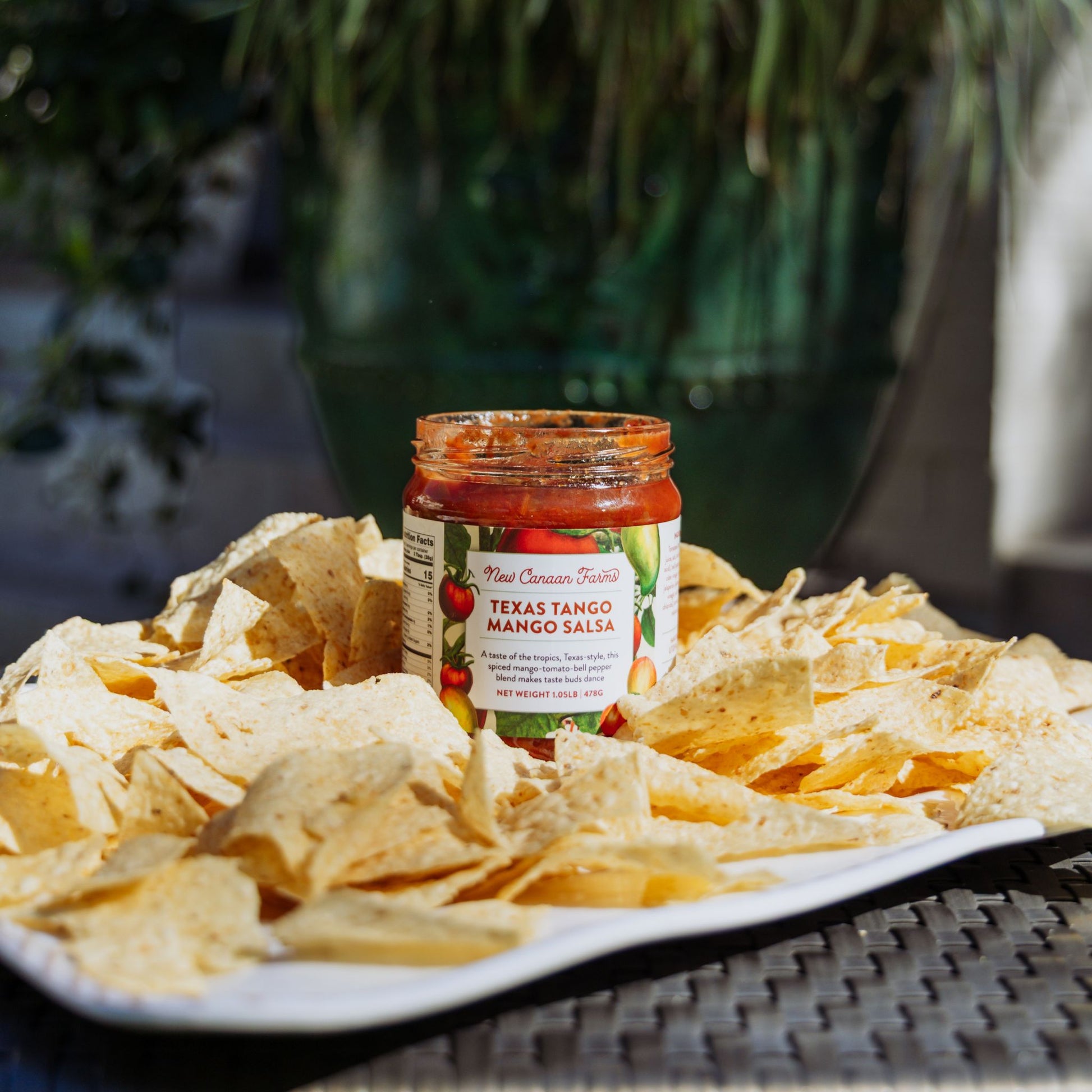 Jar of Texas Tango Mango Salsa with tortilla chips on a plate outdoors
