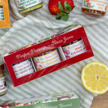 Box of New Canaan Farms Mini Texas Jams with jam jars and a lemon on a striped cloth