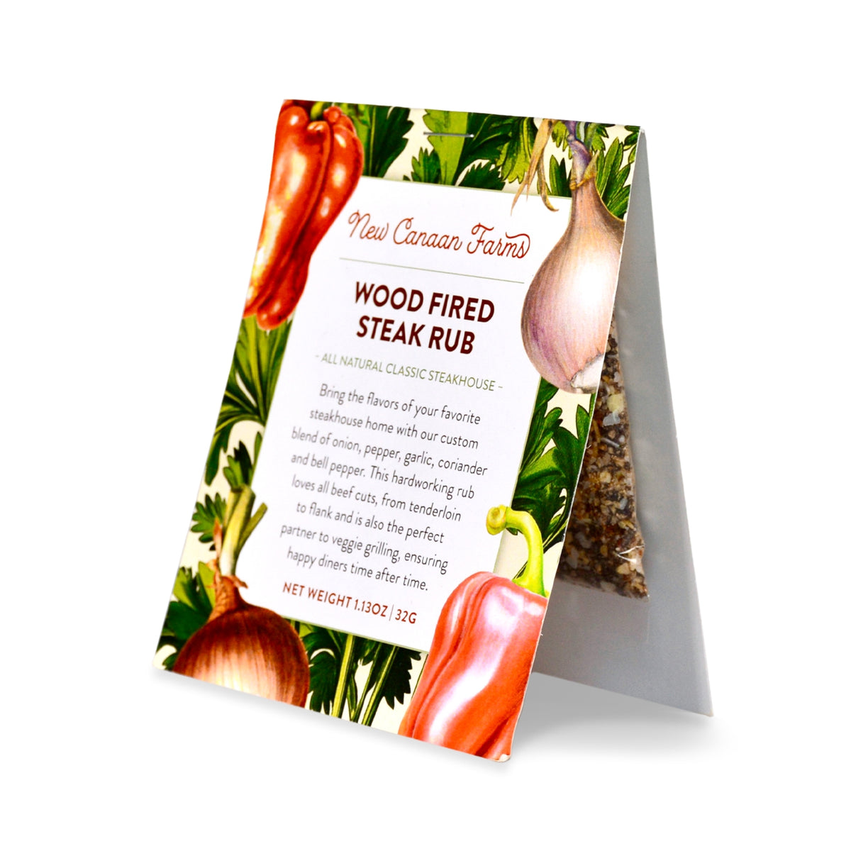 A packet of New Canaan Farms Wood-Fired Steak Rub standing upright with red peppers and an onion on the label