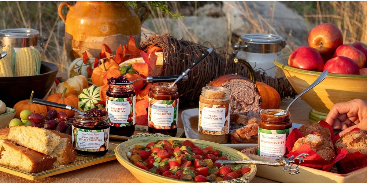 New Canaan Farms jams and spreads on a fall table with pumpkins, apples, bread and a cornucopia