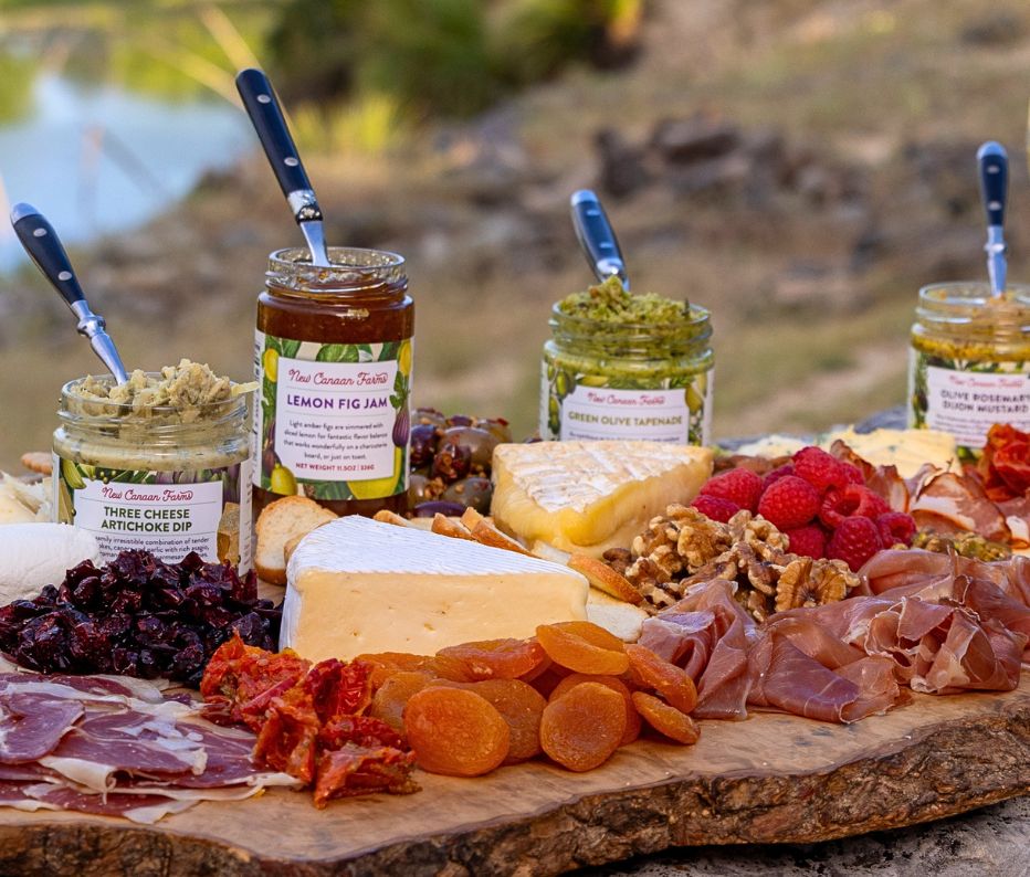Three Cheese Artichoke Dip, Lemon Fig Jam, Green Olive Tapenade and Olive Rosemary Dijon Mustard on a cheese and charcuterie board