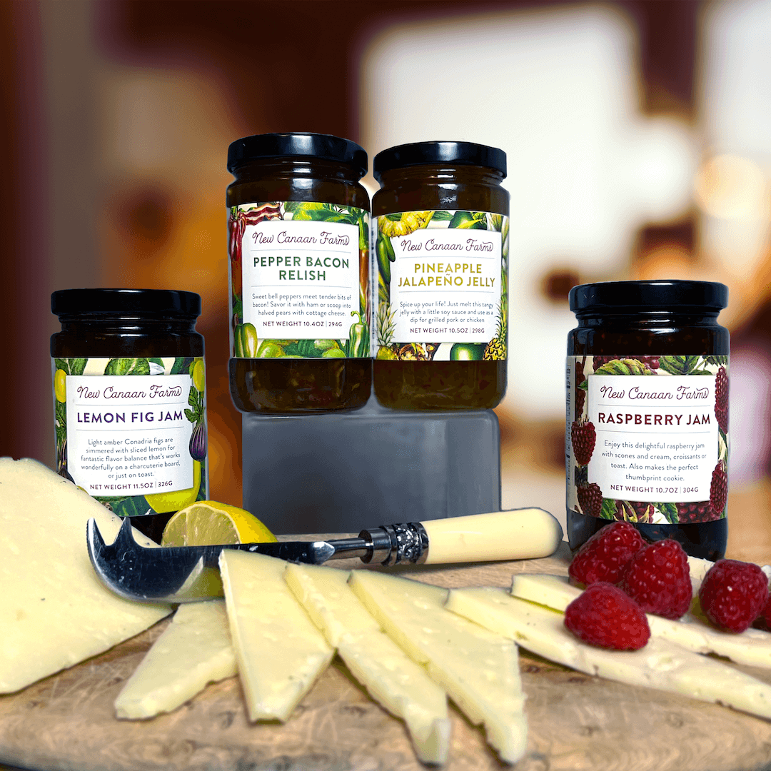 Four sweet and savory jams pictured with manchego cheese and raspberries