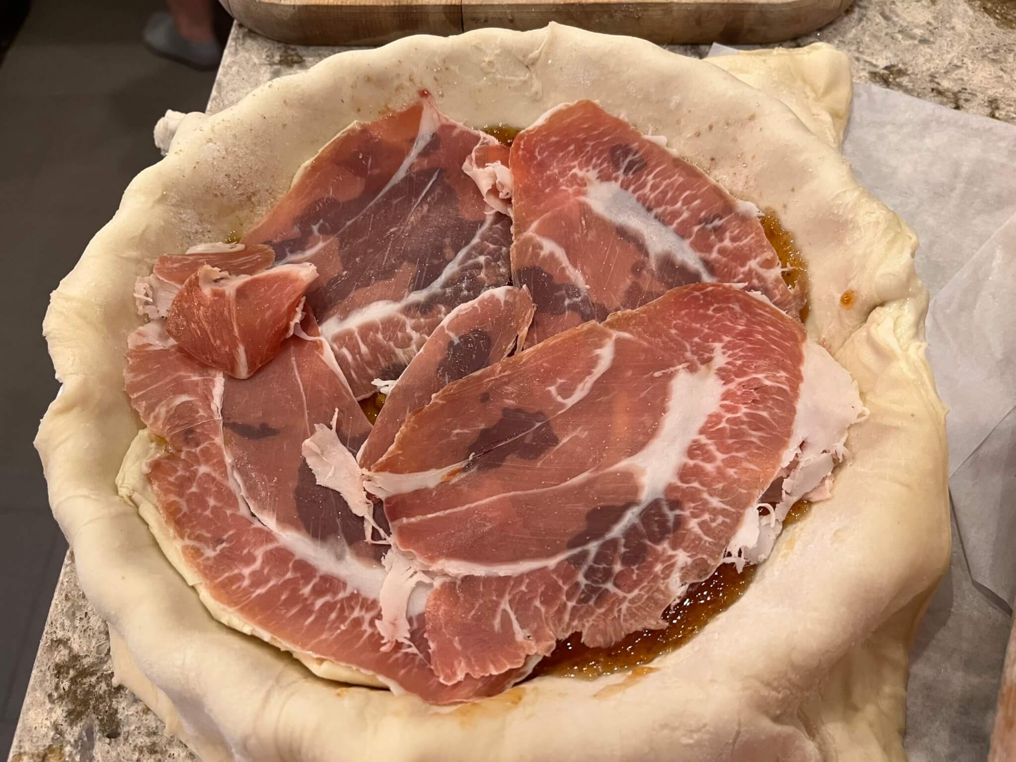 Lemon Fig, Prosciutto and Goat's Cheese Tart being made - this image shows the prosciutto layered on top of the New Canaan Farms jam that has been spread on a rolled out pastry case