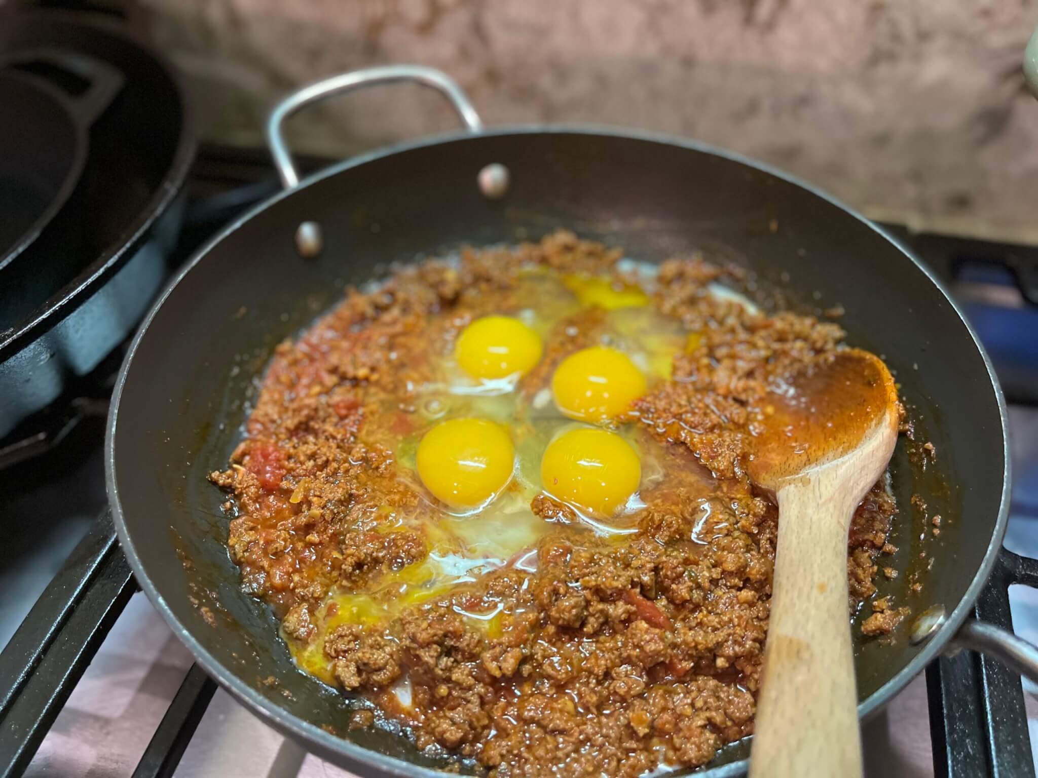 4 eggs cracked into a frying pan of cooked bulk chorizo