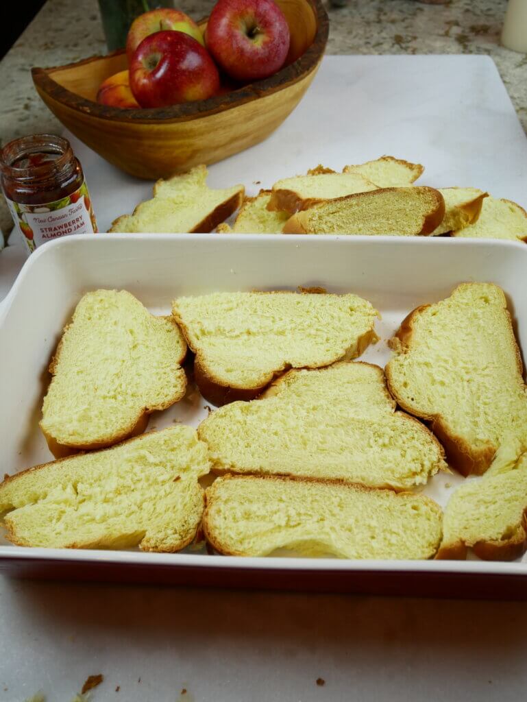 Sliced of brioche arranged in a baking dish to make bread pudding