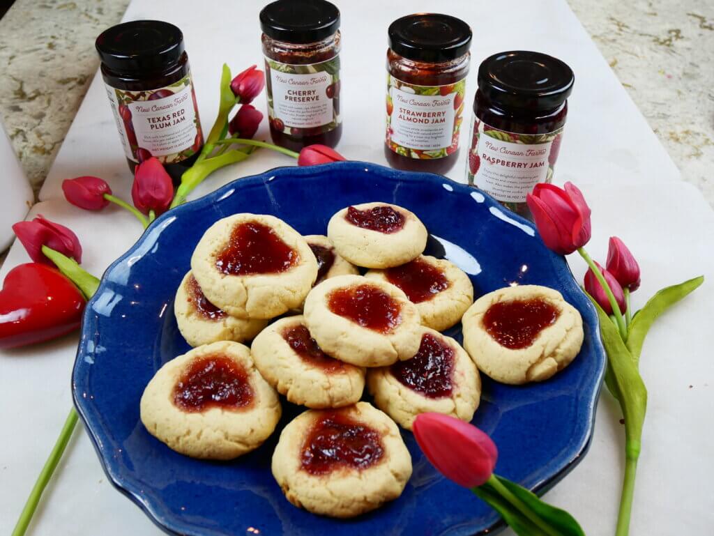 A plate of Valentine cookies with 4 New Canaan Farms red jams; Strawberry Almond, Cherry Preserves, Raspberry and Texas Red Plum
