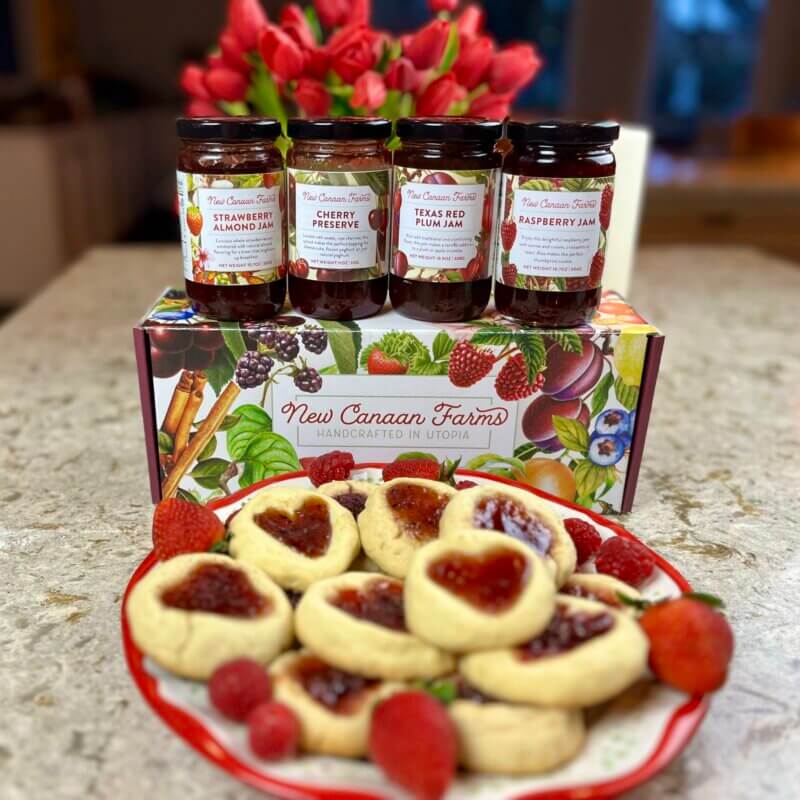 New Canaan Farms Valentine gift box with a dish of valentine jam cookies. Jams displayed are Cherry Preserves, Raspberry Jam, Strawberry Almond Jam and Texas Red Plum Jam