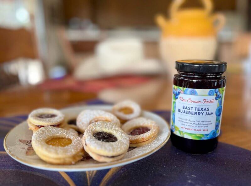 A jar of New Canaan Farms Blueberry Jam with a plate of jam cookies
