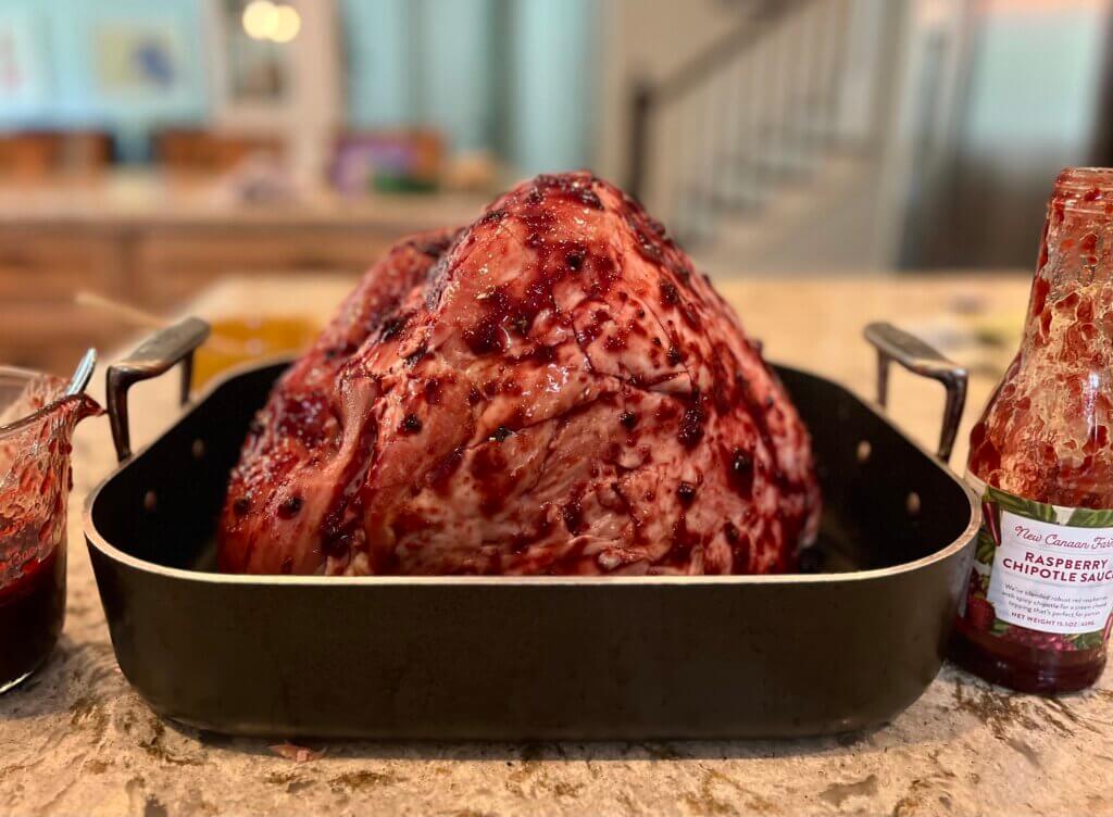 A large ham butt studded with cloves and covered with New Canaan Farms Raspberry Chipotle Sauce, ready to go in the oven