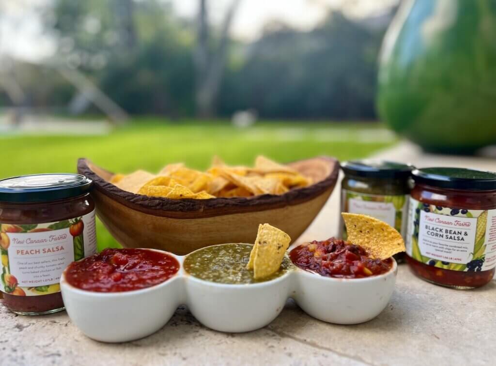A trio of salsas in white bowls with corn tortilla chips