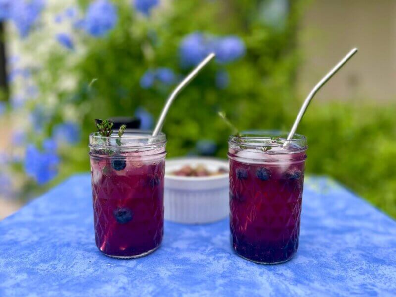 Two mason jars filled with blueberry gin cocktail, made with New Canaan Farms East Texas Blueberry Jam