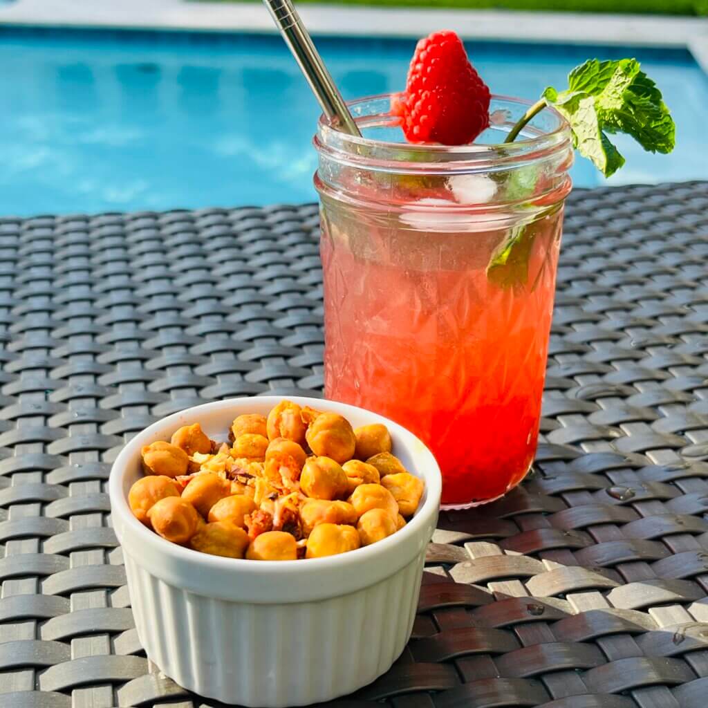 Raspberry Rum cocktail made with New Canaan Farms raspberry jam, with a bowl of spicy roasted chickpeas