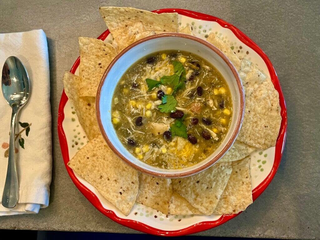 A bowl of chicken tortilla soup, served on a bed of tortilla chips