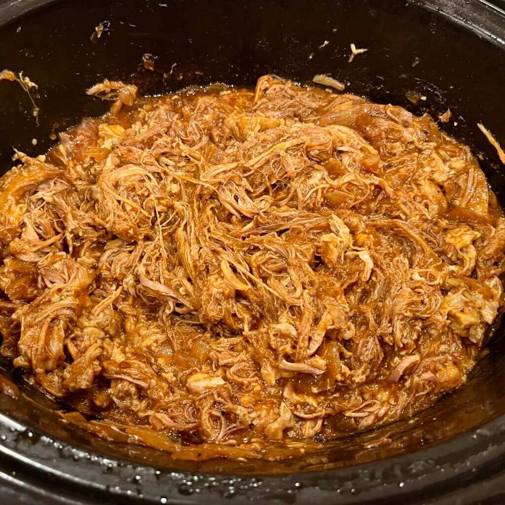 A large slow-cooker filled with pulled pork, cooked with New Canaan Farms Texas BBQ sauce