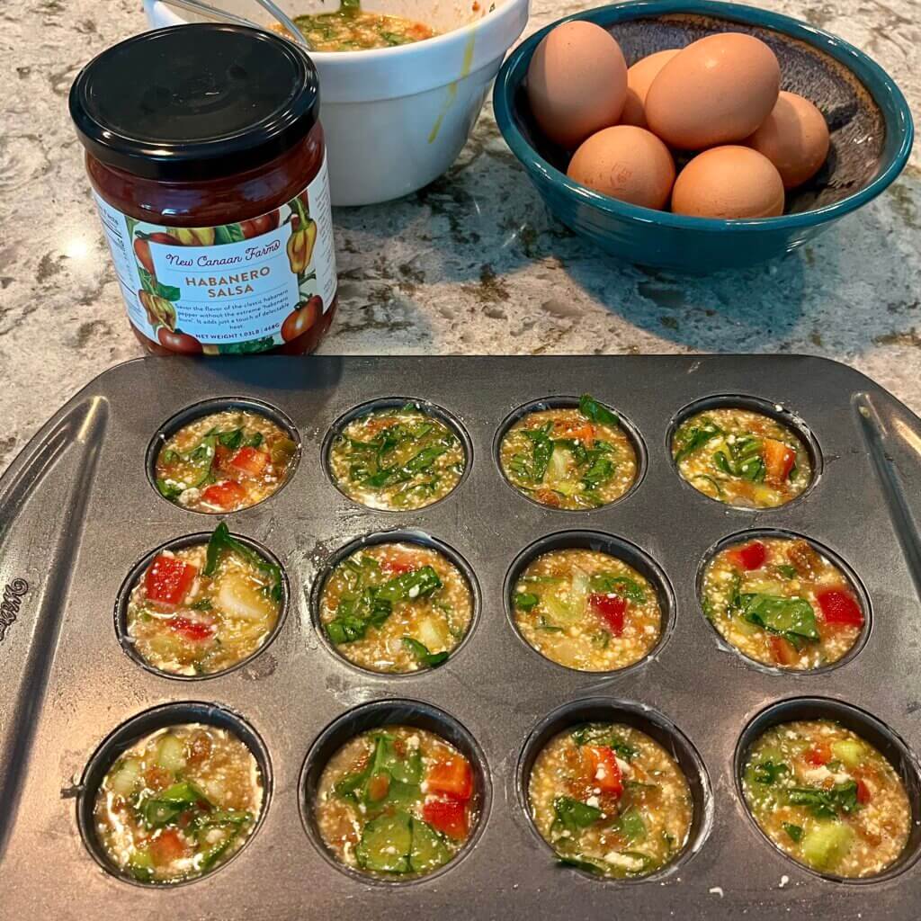 An egg, spinach and red pepper mixture in a mini muffin pan