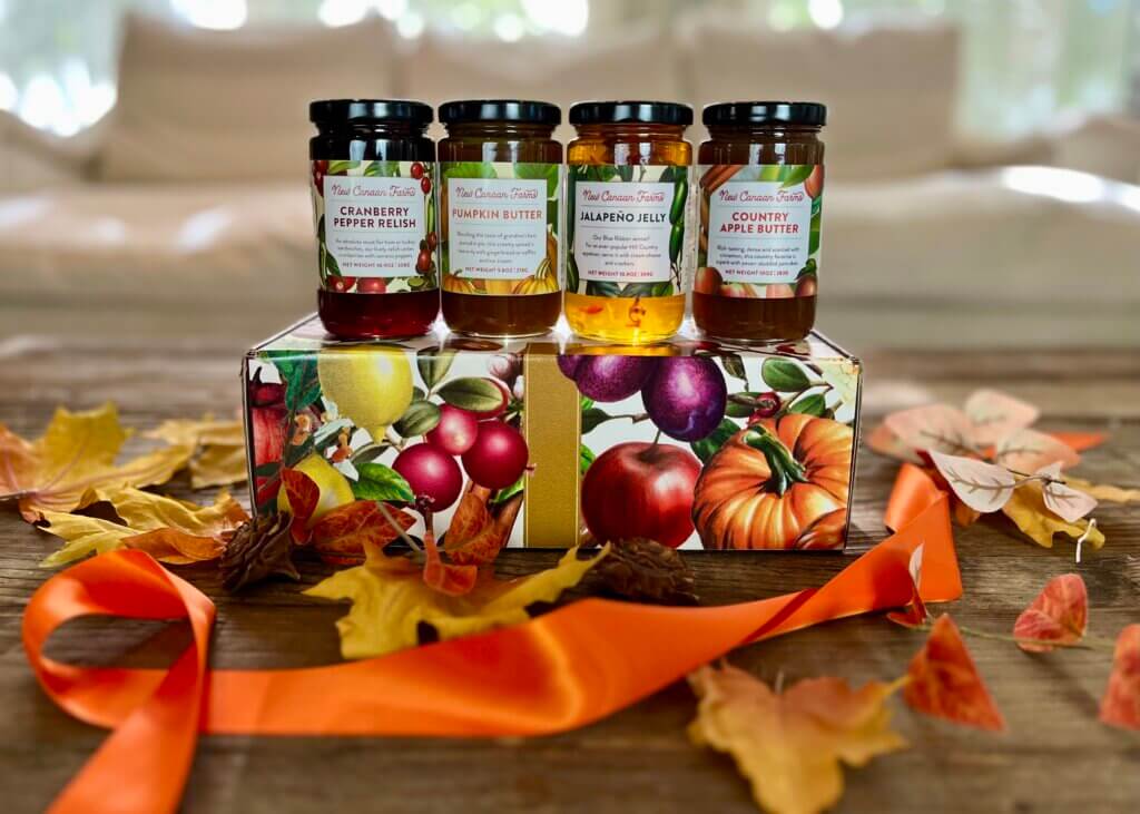 4 Fall-inspired New Canaan Farms jams; Cranberry Pepper Relish, Country Apple Butter, Jalapeño Jelly and Pumpkin Butter, displayed on a beautiful seasonal gift box