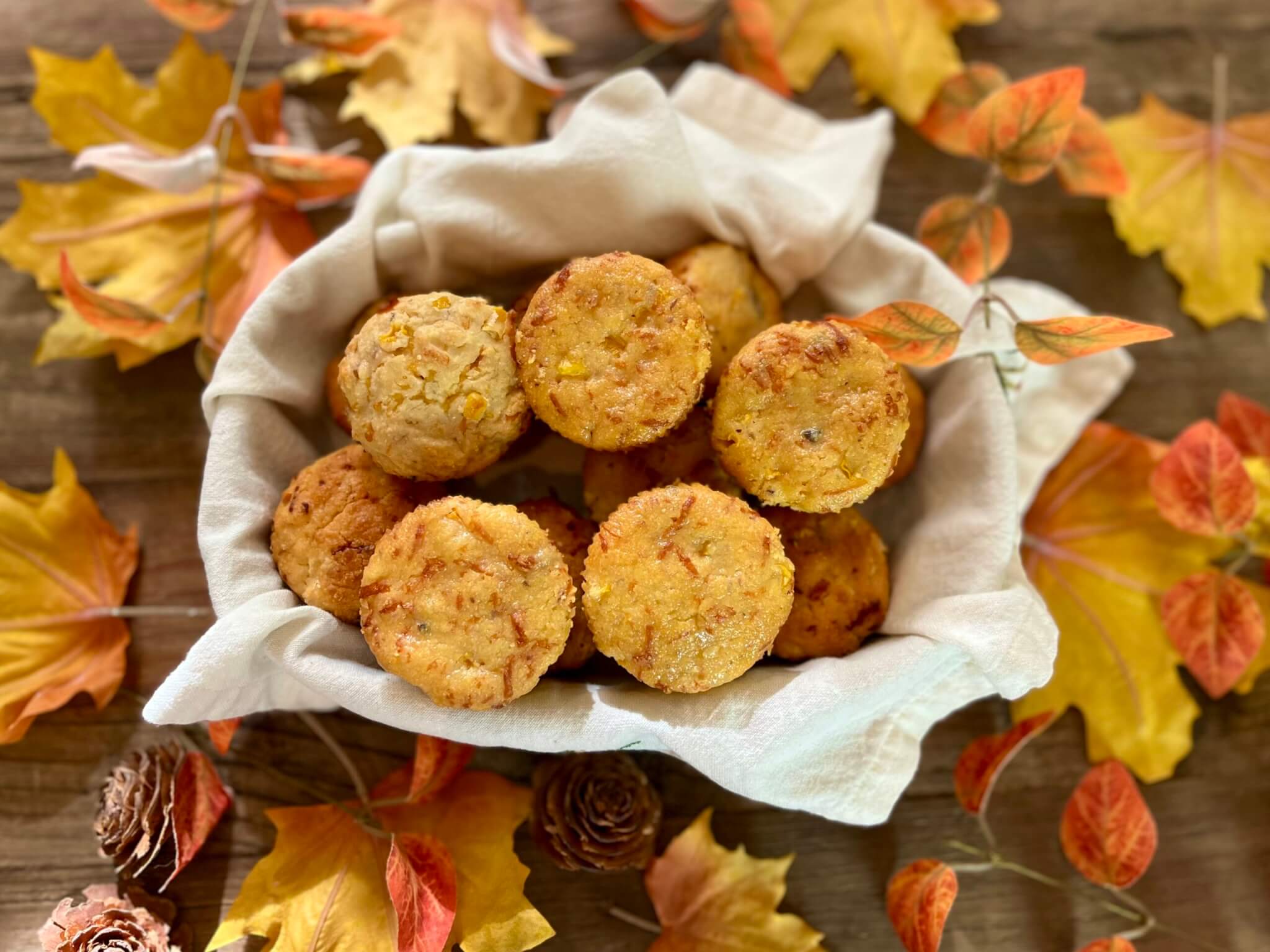 A bowl of Cranberry Pepper Cornbread muffins, surrounded by fall leaves