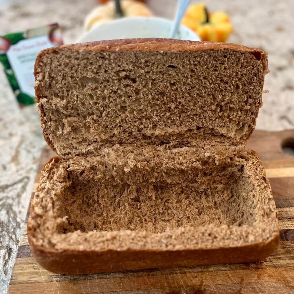 A loaf of wheat bread, with the top partially cut off, and the insides scooped out to make a coffin shape