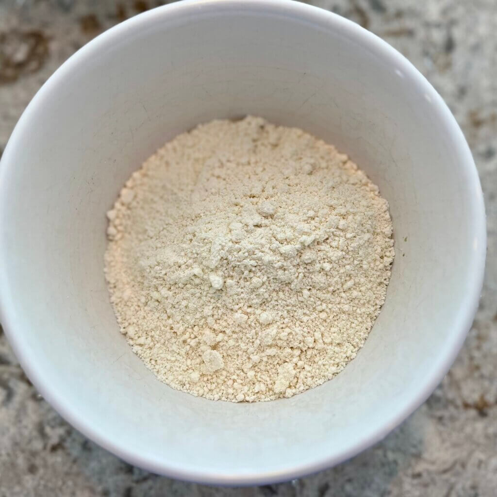 A white ceramic bowl containing flour and butter mixed together