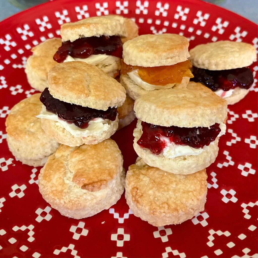 A red plate filled with mini scones, served with jam and cream