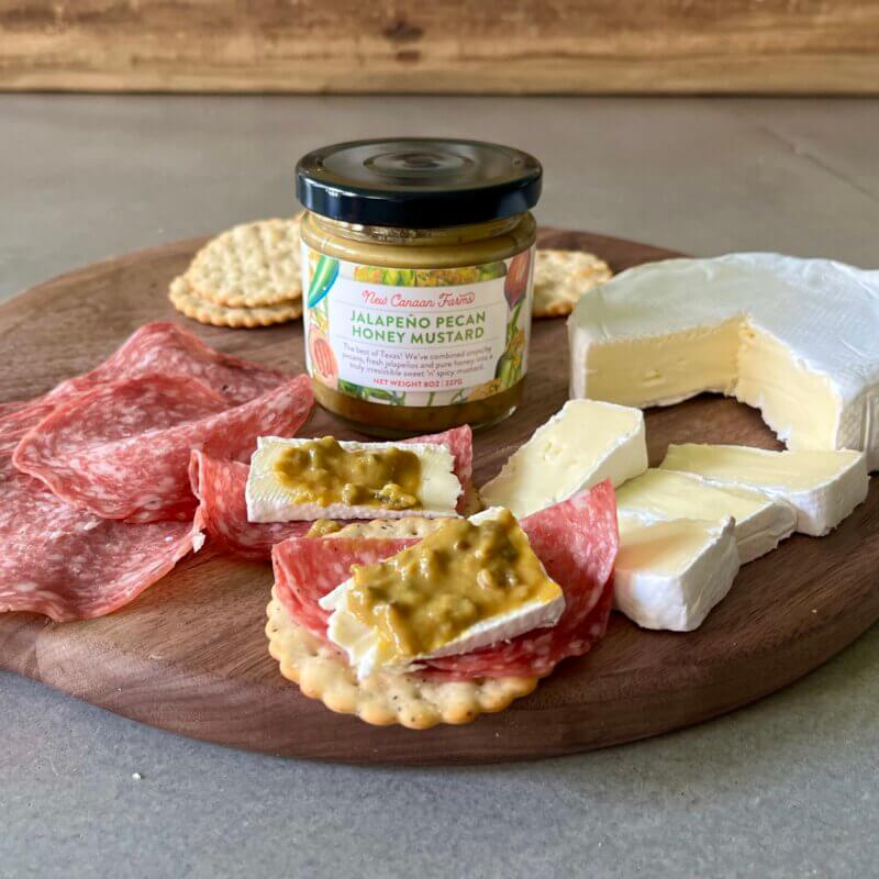 A charcuterie platter, garnished with New Canaan Farms Jalapeño Pecan Honey mustard