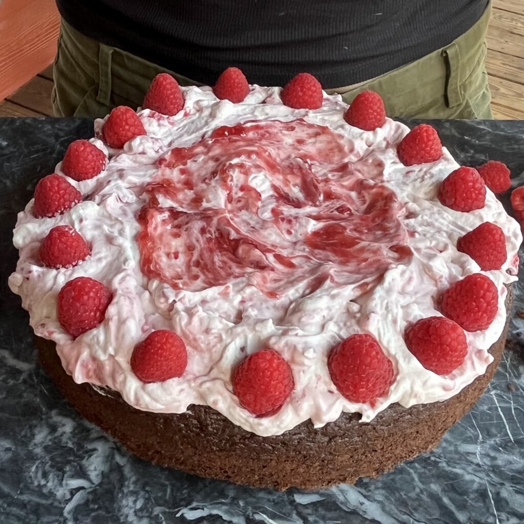 A chocolate raspberry cake, made with New Canaan Farms raspberry jam and garnished with fresh raspberries