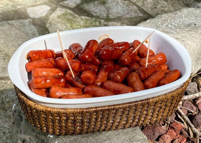 A white serving dish containing little smokies cooked in Bourbon Molasses Sauce