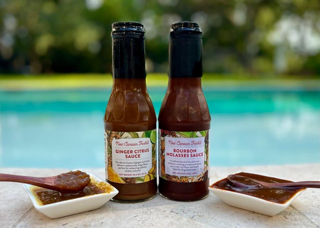 A jar of New Canaan Farm's Ginger Citrus Sauce and Bourbon Molasses Sauce in front of a swimming pool