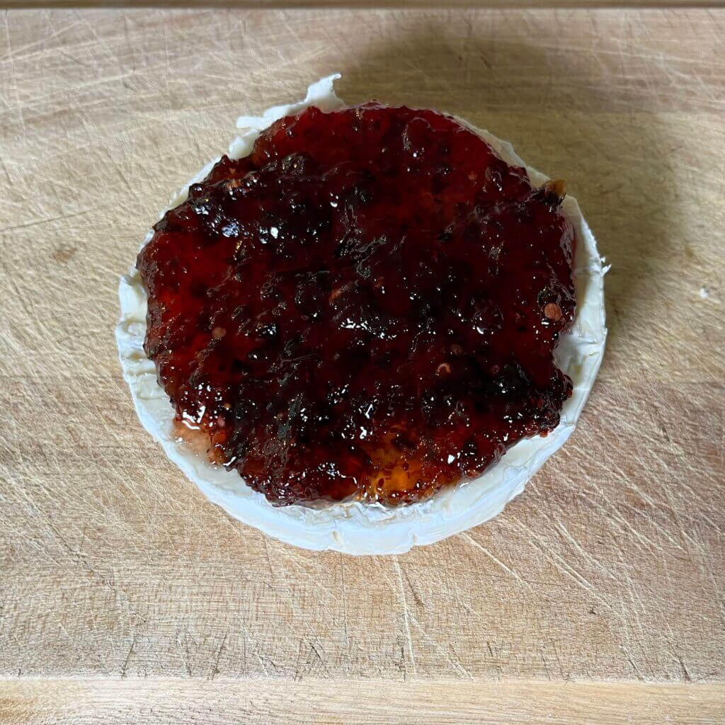 A round of brie with New Canaan Farms Cranberry pepper Relish spooned over